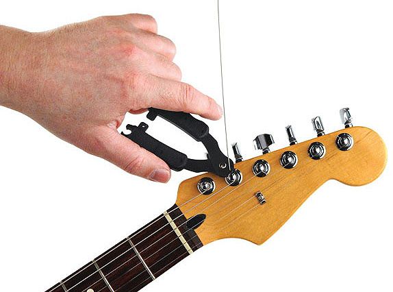 Hand turning a black guitar string winder on a guitar headstock