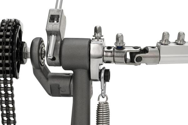 Close-up of double bass drum pedal cam, chain drive, and metal linkage components