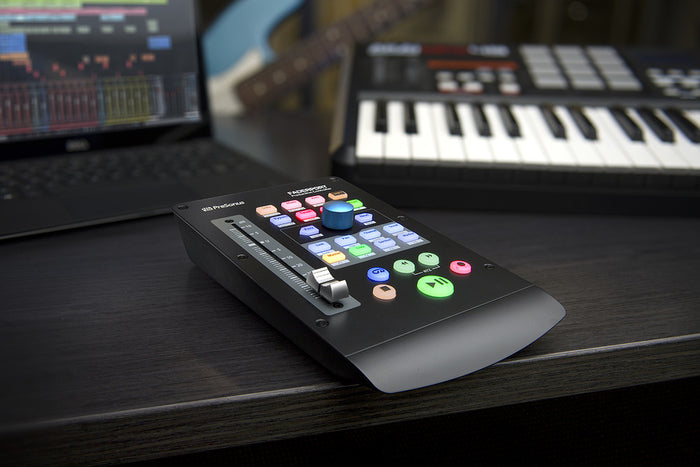 Black fader controller with colorful buttons and large rotary knob on desk